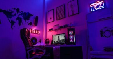 A gaming workspace with a computer, neon signs, and wall art in purple
